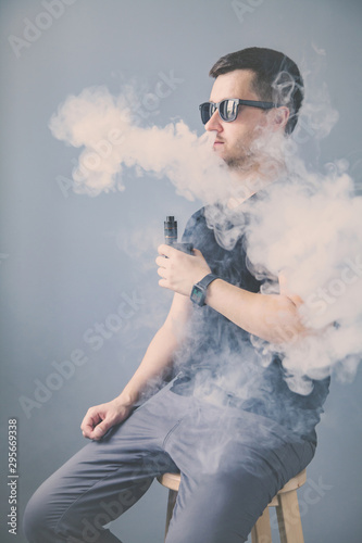 vaping man holding a mod. A cloud of vapor.