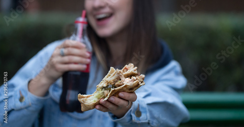 Young woman eating fast food on the street.