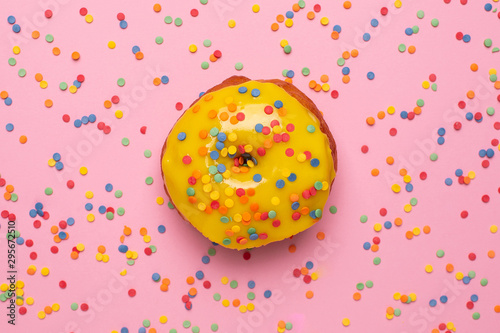 Sweet yellow donut with sprinkle on a pink background flat lay