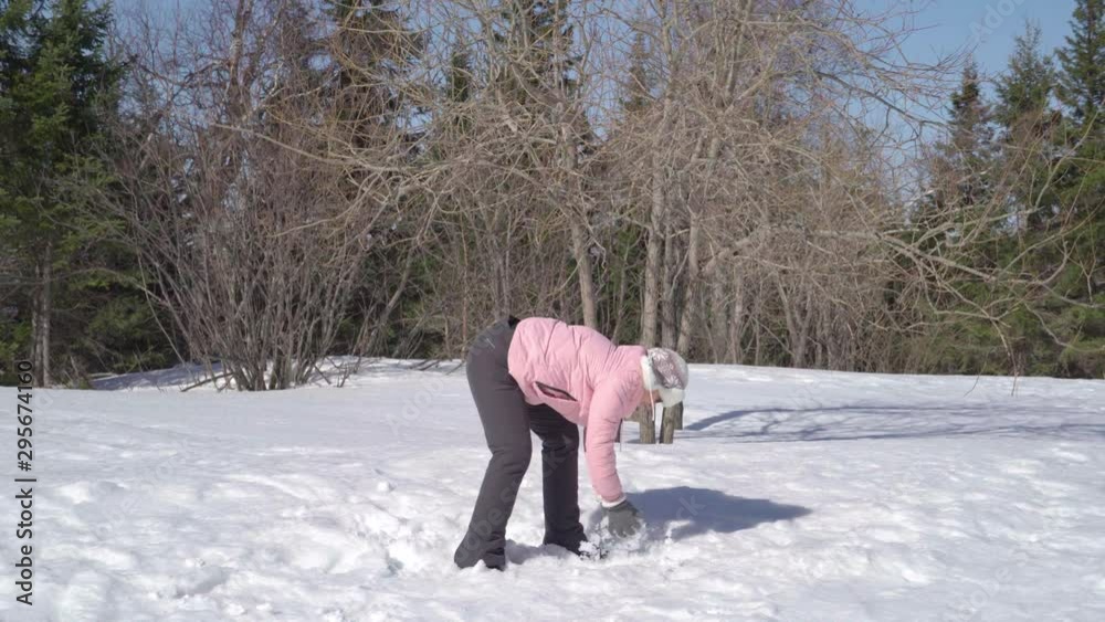 An elderly lady throws snowballs. In winter New Year's weather on a beautiful day.