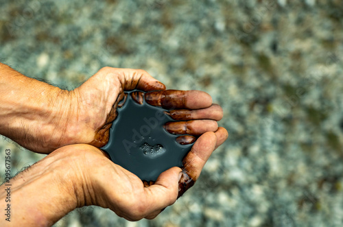 Mineral oil in the hands of man. Caucasian hands cupped with black rock-oil photo