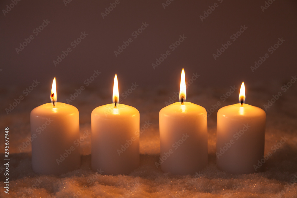 Vier brennende Kerzen im Schnee