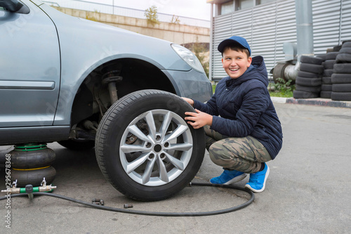  Children's auto mechanic changes the wheel on a car. Wheel repair.