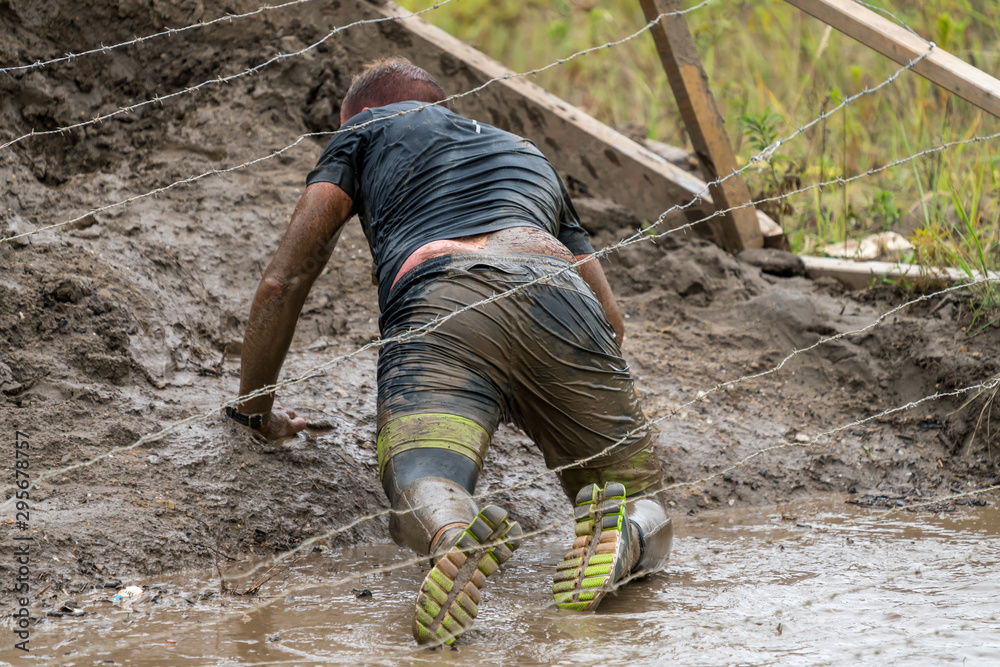 Athlete crawling under barbed wire at an obstacle course race Athlete crawling under barbed wire at an obstacle course race