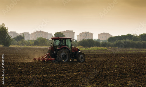 Tractor with soil preparing  concrete buildings in background