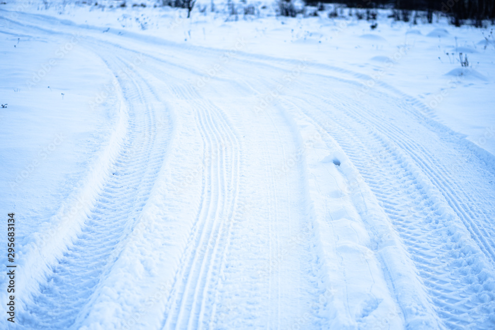 Tread texture of car wheels on snow. Winter road in January, December. Rural area and background of tractor tracks in the snow