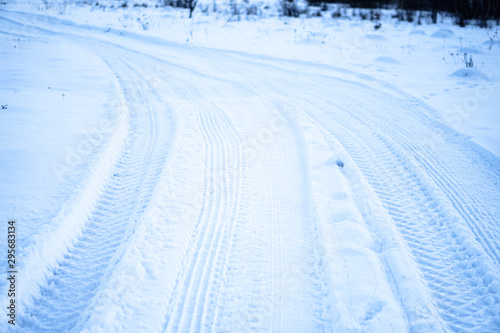 Tread texture of car wheels on snow. Winter road in January, December. Rural area and background of tractor tracks in the snow