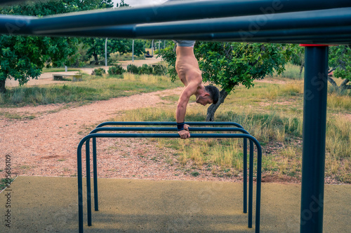 Atleta fuerte Atlético brutal, hombre haciendo ejercicios de dominadas en un travesaño en el gimnasio de la calle al aire libre