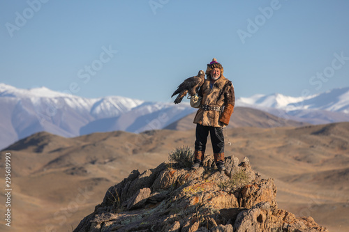 Old traditional kazakh eagle hunter posing with his golden eagle in the mountains. Ulgii, Western Mongolia.