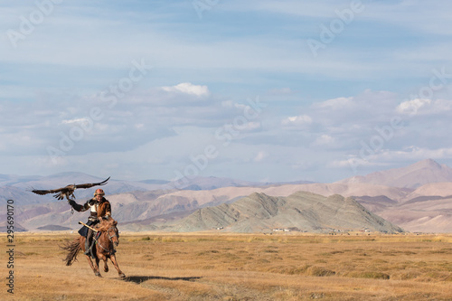 Kazakh eagle hunter galloping with his golden eagle. Ulgii, Western Mongolia.