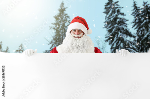 Santa Claus with blank poster in winter forest © Pixel-Shot