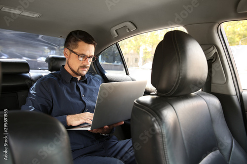 Successful businessman with laptop in modern car