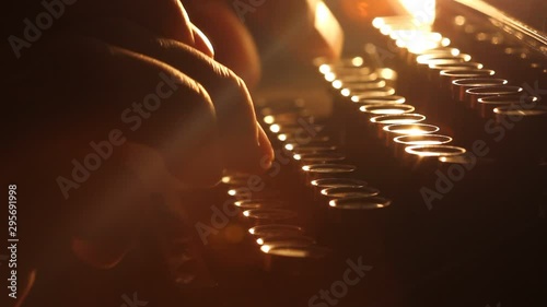 Close up shot of man typing on old vintage retro typewriter; backlit; news, media or communication concept