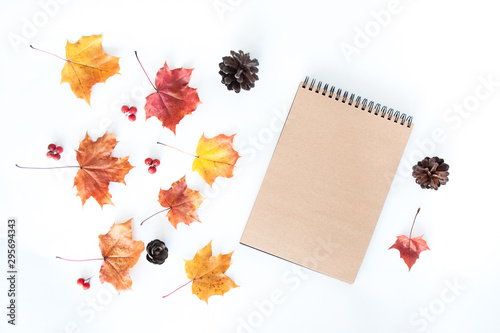 Autumn composition with empty craft notebook and autumn leaves on a white background, flat lay