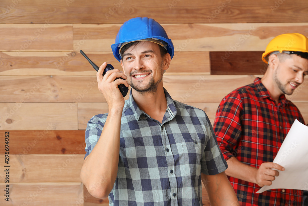Fototapeta premium Portrait of male architect with portable radio transmitter and his team on wooden background