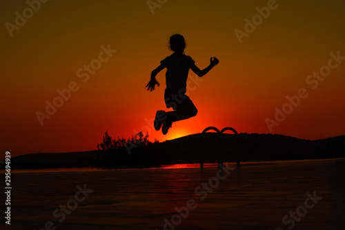 silhouette of young a girl jumping on the beach at sunset