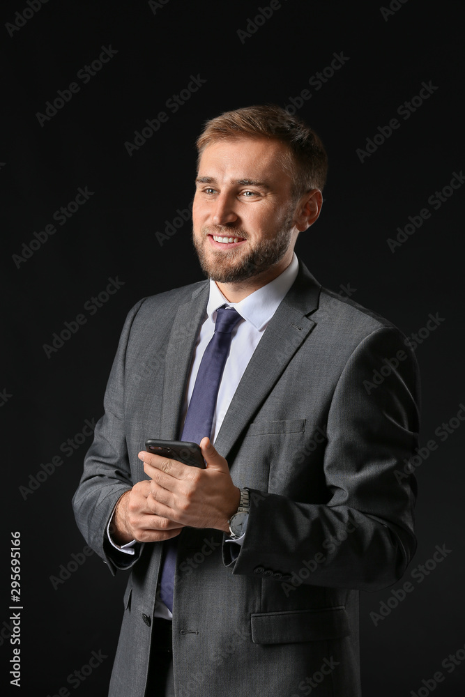 Portrait of handsome businessman with mobile phone on dark background Portrait of handsome businessman with mobile phone on dark background