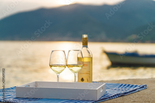 Sunset view of two wine glasses and bottle of white wine on the background of Kotor bay, Montenegro. photo