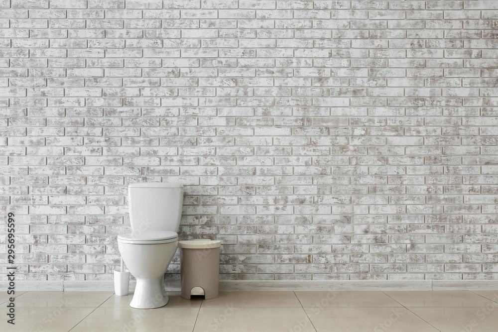 Toilet bowl near light brick wall Toilet bowl near light brick wall