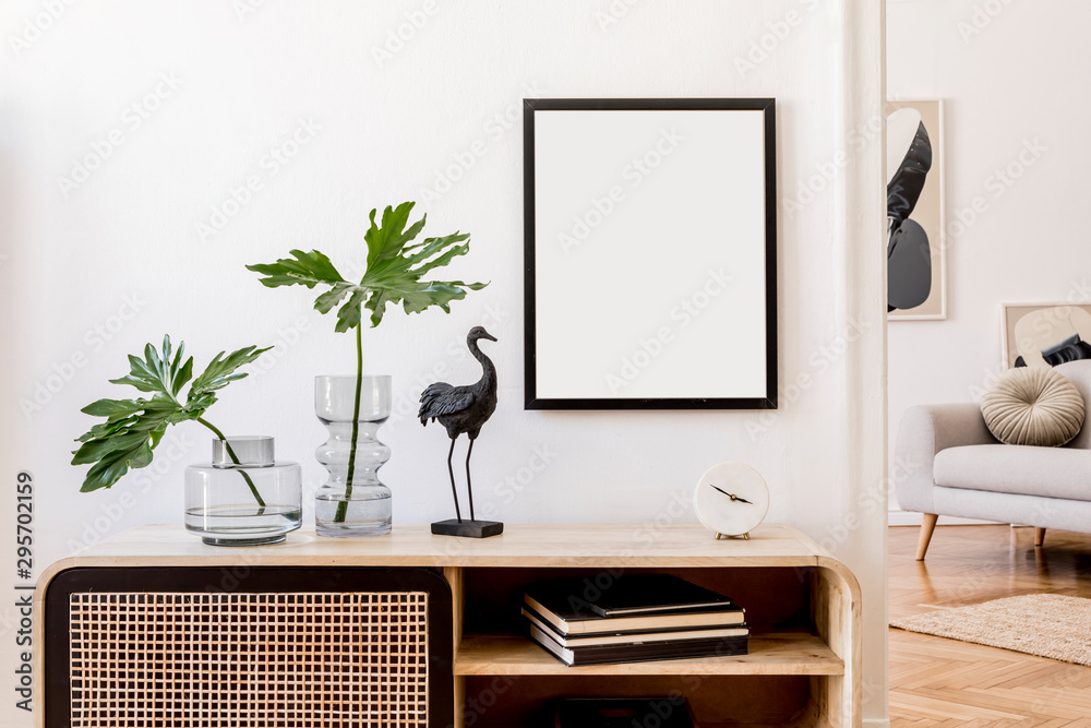 Obraz Modern scandinavian home interior with mock up photo frame, design wooden commode, black sculpture, tropical leaf, gray sofa and personal accessories. Stylish home decor. Template. Ready to use.