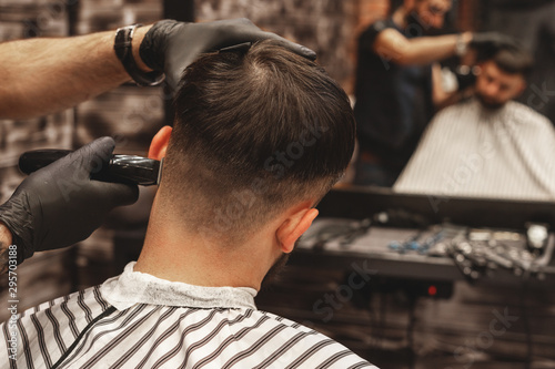 Haircut head in barbershop. Barber cuts the hair on the head of the client. The process of creating hairstyles for men. Barber shop. Selective focus.