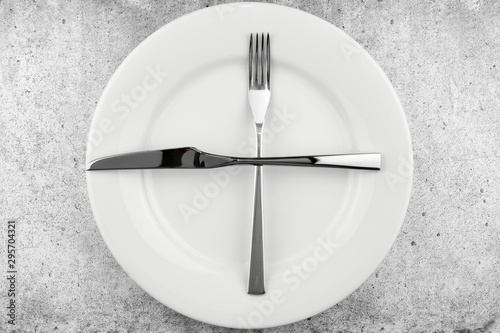 Table setting. Empty plate, knife and fork on a light concrete background. A fork and a knife lie on a plate, waiting for the next dish. Top view and flat lay with copy space