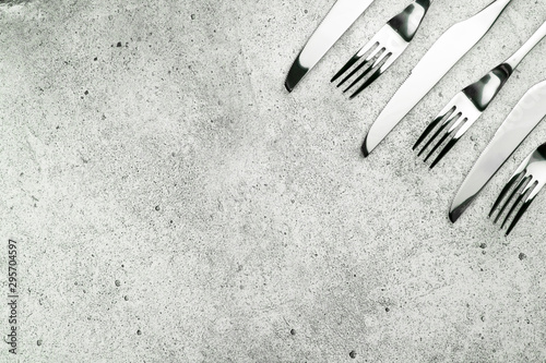Cutlery. Forks and knives on a light concrete background. Place for an inscription. Flat lay, top view, copy space.