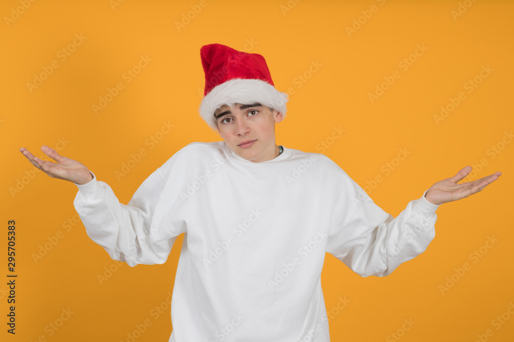 young teenage man with santa claus hat isolated on color background young teenage man with santa claus hat isolated on color background