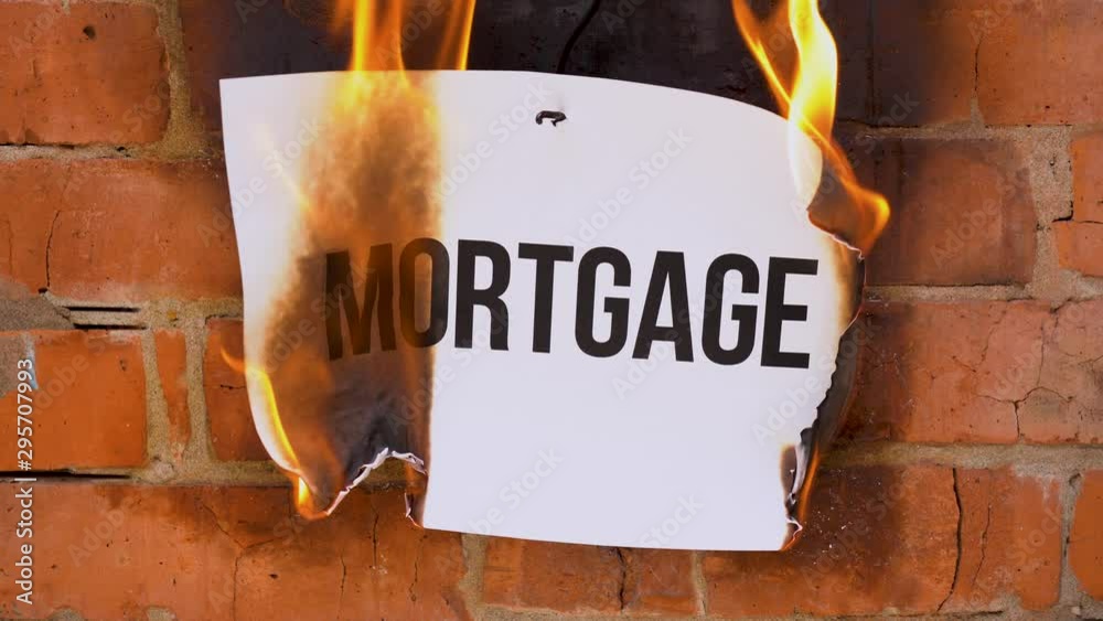 The inscription on a white A4 size sheet against the background of an orange brick wall. The paper with the black word Mortgage burns, smoke and turns into ashes. Business concept.