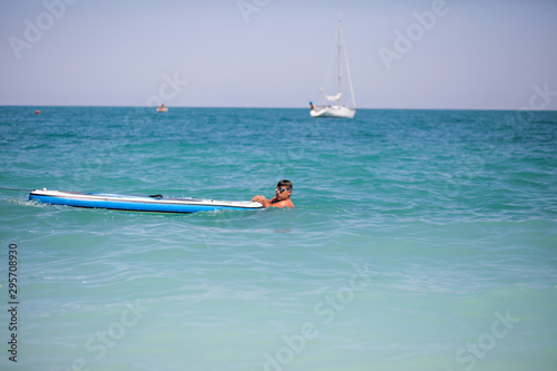Summer Adventure. Water Sports. Man with Paddle, Surf Board In Sea