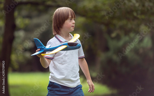 Mentally challenged boy launching a toy airplane on a summer park lawn