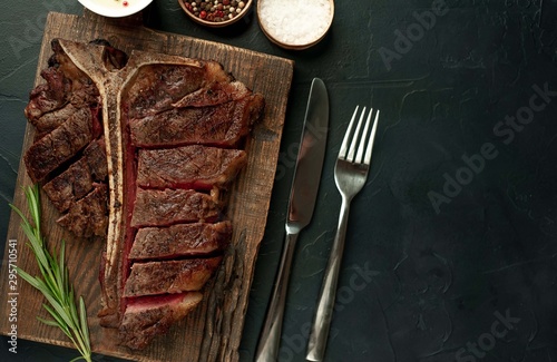 Grilled T-bone steak on a stone table. With rosemary and spices. Top view with copy space.