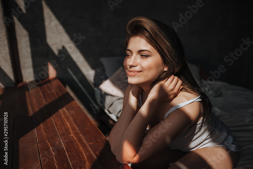 Girl sitting on the bed by the window in the sunlight © Smeilov