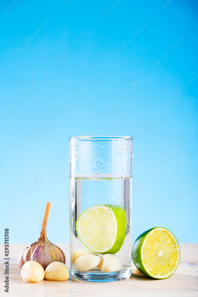 Foto de Lemon slice and garlic head in a glass with water, garlic water
