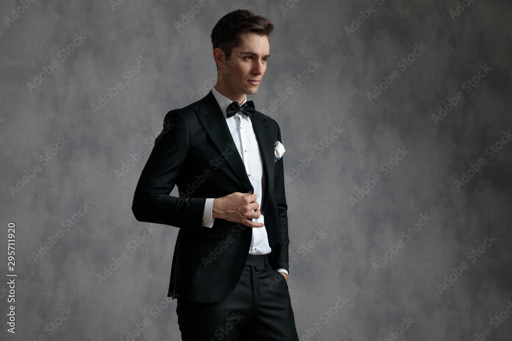 young elegant groom wearing tuxedo and arranging coat young elegant groom wearing tuxedo and arranging coat