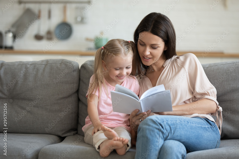 Happy mother and little daughter reading book together at home Happy mother and little daughter reading book together at home