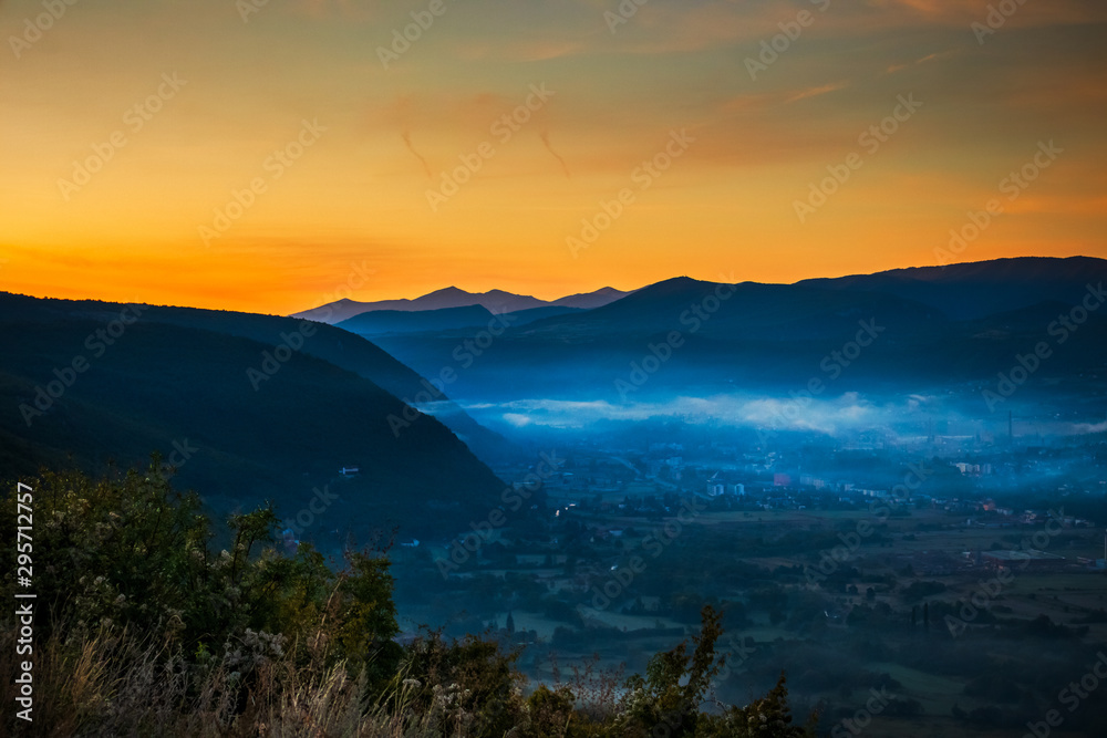 Sunrise with fog, mountains and town in the background. Drvar in Bosnia and Herzegovina.