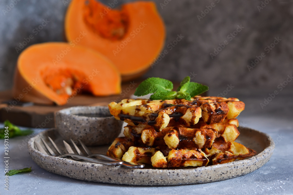 Fototapeta premium Belgian waffles with pumpkin and chocolate sauce on a concrete background with place for text.