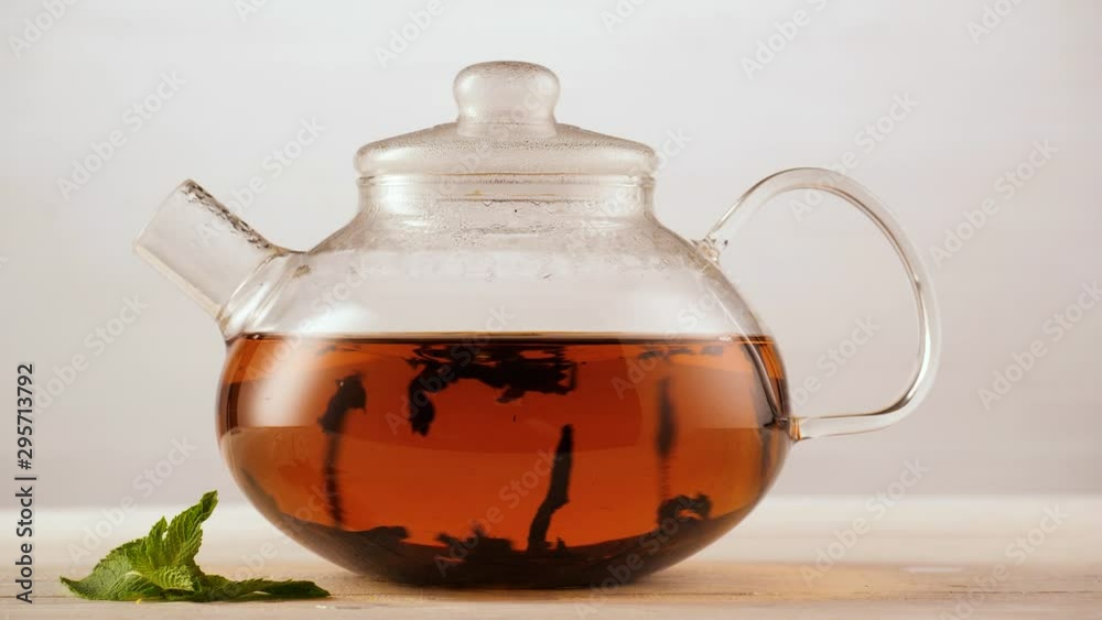 Adding water to tea leaves in a Glass Teapot on a light Grey Background. Making tea. 4k. Adding water to tea leaves in a Glass Teapot on a light Grey Background. Making tea. 4k.