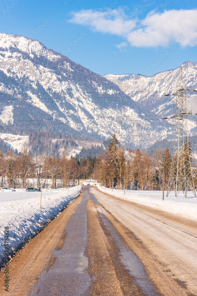 Empty, snow-covered, streight winter, asphalt  road to Weißenbach with mountains in the background, Dachstein massif, Liezen District, Styria, Austria, Europe
