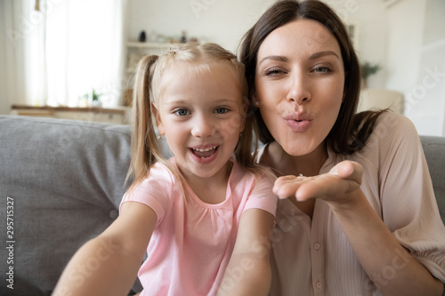 Head shot daughter and mother taking selfie, sending blow kiss