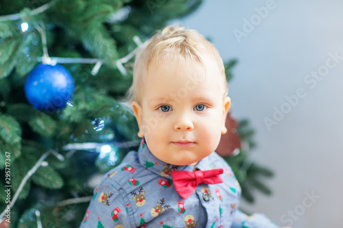 Small boy in Santa suit plays near new-year tree