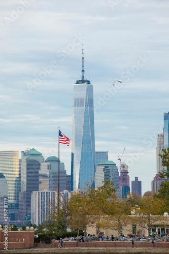 Downtown Manhattan and the Freedom Tower as seen from Ellis Island with flag in foreground