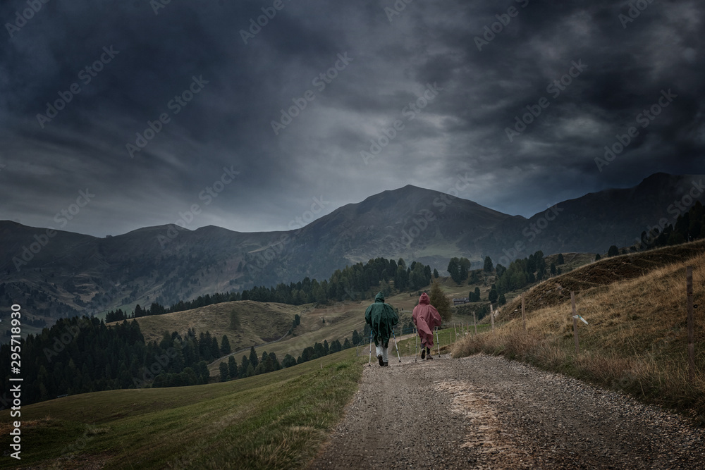 Hikers hiking in Alpe di Siusi - Seiser Alm with dramatic sky