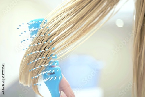 lock of wet blond hair combed by a blue comb. photo