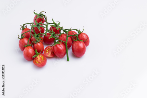 Grape or cherry tomato branch. Pile of red grape tomatoes isolated on white background, soft light, angle view, studio shot.