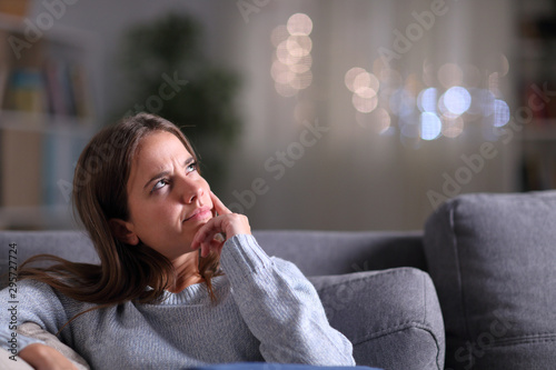 Doubtful pensive woman looking at side at home in the night photo