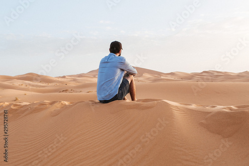 A person sitting in the desert sahara watching the sunrise