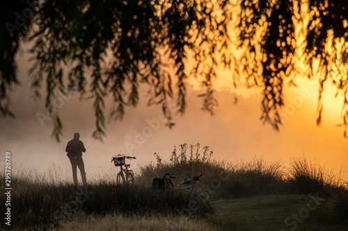 Silhouette of a man standing by a bicycle at sunset, Bushy Park, Richmond Upon Thames, United Kingdom photo