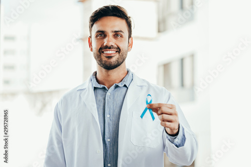 Prostate Cancer Awareness. Doctor man holding light Blue Ribbon for supporting people living and illness. Men Healthcare and World cancer day concept